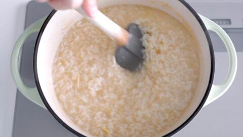 Stirring Arroz Caldo to prevent the rice from burning to the bottom of the pot.