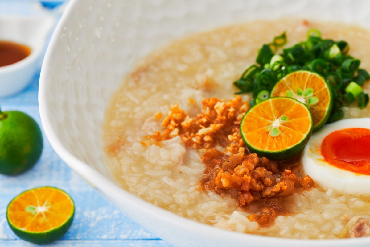 This mouthwatering bowl of Arroz Caldo (Filipino Chicken and Rice Porridge) is garnished with chicken cracklins, crispy garlic, a soft boiled egg, scallions, and Calamansi.