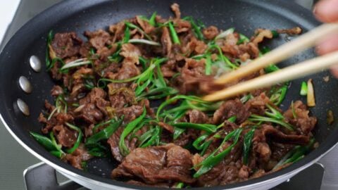 Cooked beef with green onions in a frying pan.