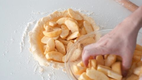 Filling the bottom pie crust with apples.