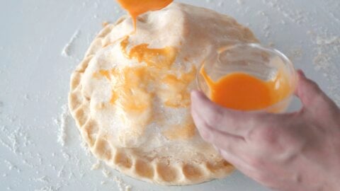 Brushing on an egg wash onto the top crust of a pie.