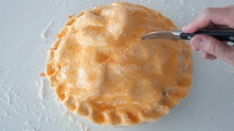 Cutting holes into the top of an apple pie to allow steam to vent.