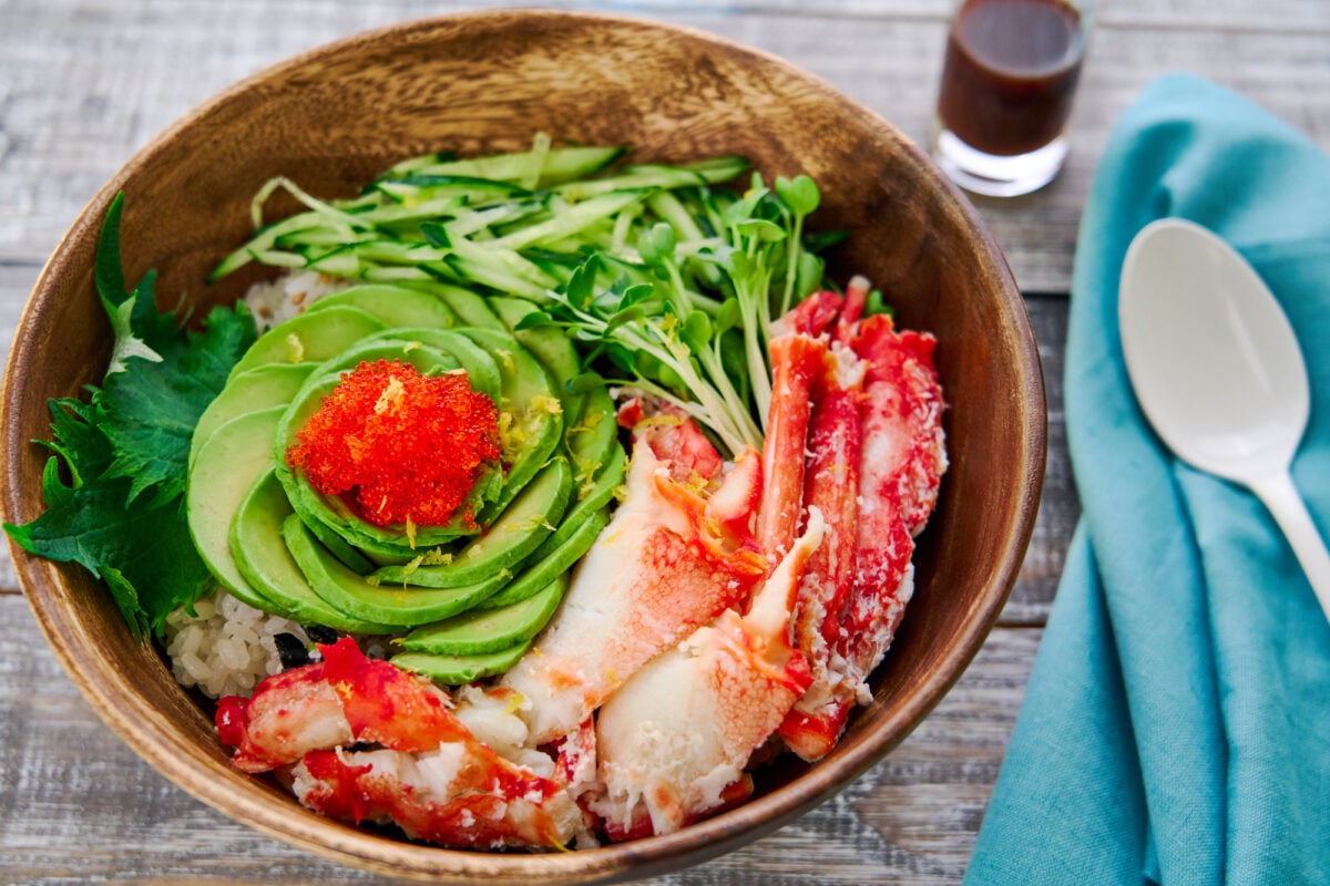 Turning California roll into a sushi bowl with crab, avocado, tobiko, and cucumbers on a bed of sushi rice and nori.