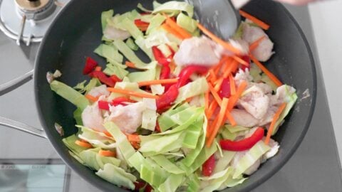 Stir-fried cabbage, carrots, red bell peppers and chicken for making Chicken Chow Mein.