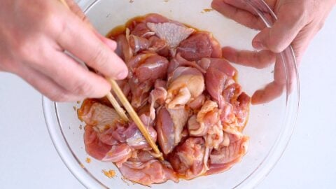 Marinating chicken thighs in soy sauce, ginger, and sake for making karaage.