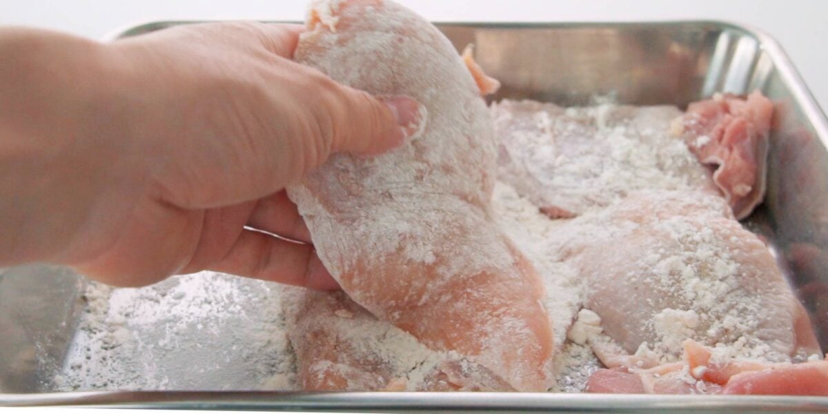 Dusting chicken with flour.