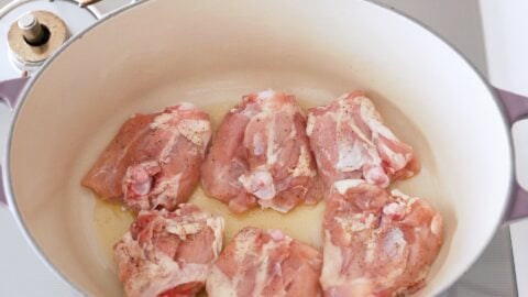 Seasoned chicken being browned in a Dutch oven for making Chicken Paprikash.