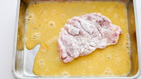 Dip the chicken cutlet in an egg wash to help the breading adhere.