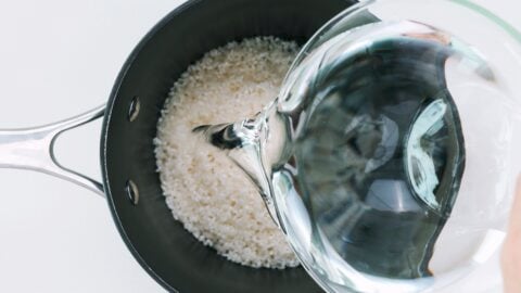 Adding water to a pot of sushi rice.