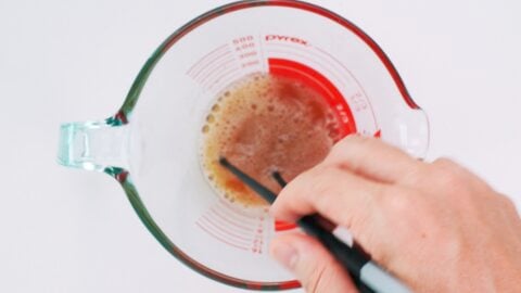 Mixing sushi vinegar together in a glass container with chopsticks.