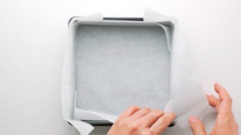 Lining a brownie pan with parchment paper.