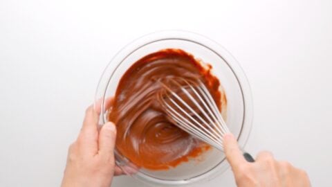 Emulsifying the wet ingredients for brownies together in a glass bowl.