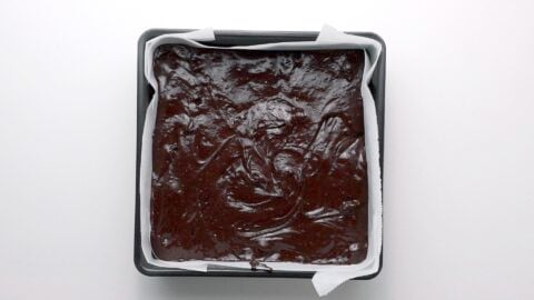 Fudgy brownie batter in a parchment lined brownie pan.