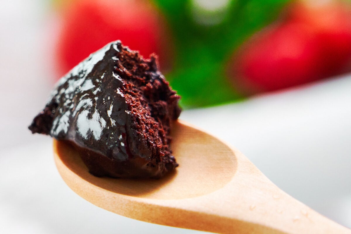 A spoonful of chocolate mug cake enrobed in a rich fudgy chocolate sauce.