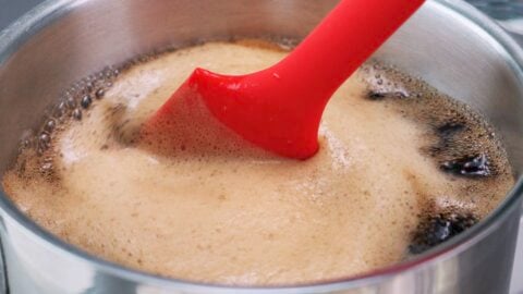 Stirring coffee jelly in a pot with a red spatula.