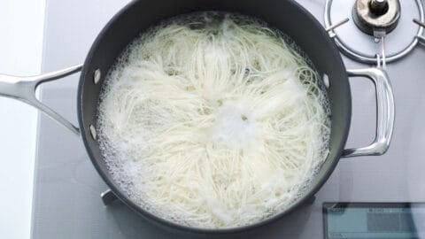 Somen noodles boiling in a large pot.