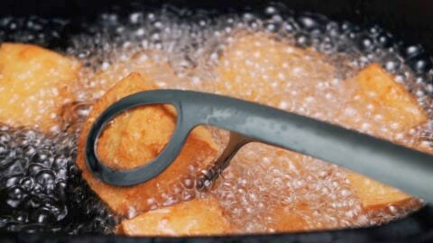 Crispy tofu bites coming out of hot oil.