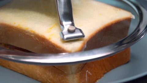 Pan-frying curry bread with a drop lid to press the sandwich together.