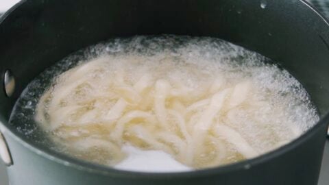 Udon noodles boiling in a pot.