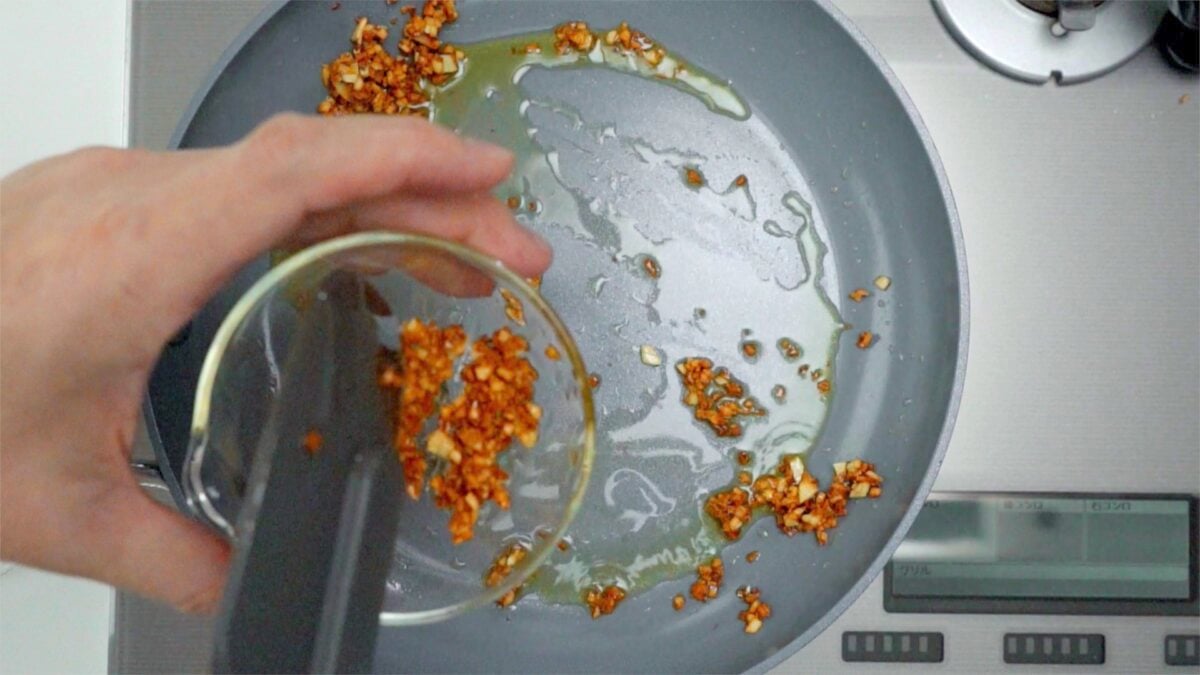 Transferring crisp garlic to a bowl.