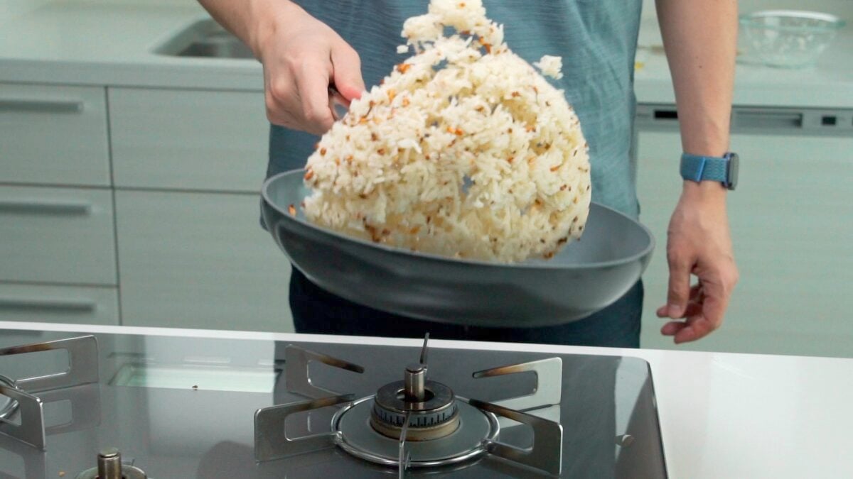 Tossing garlic rice in a pan.