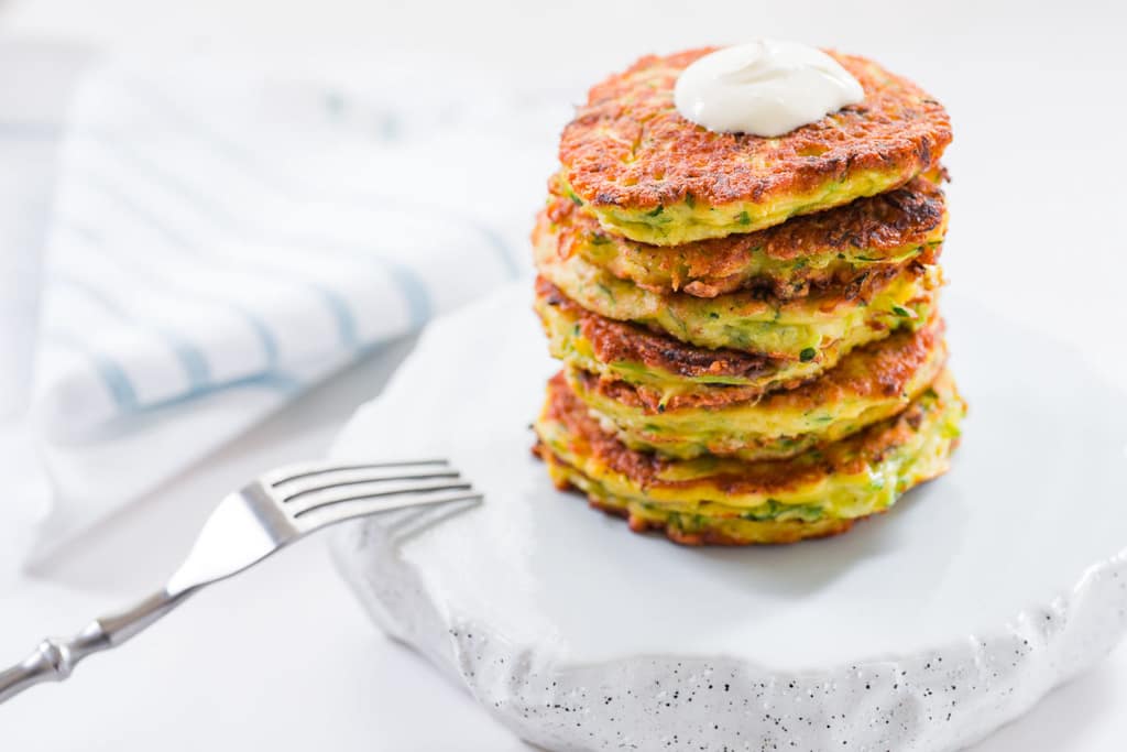 A stack of delicious zucchini pancakes with a dollop of sour cream.