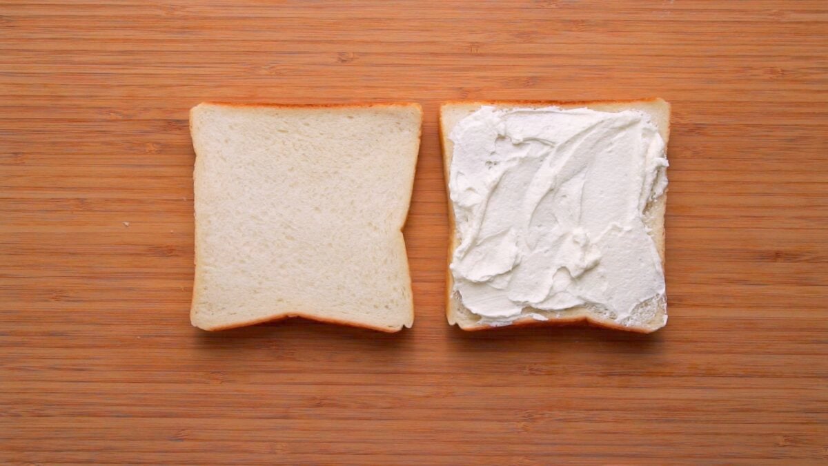 Two slices of sandwich bread with whipped cream on one.