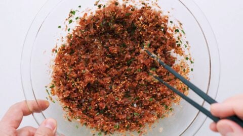 Mixing furikake seasoning in a glass bowl with chopsticks.