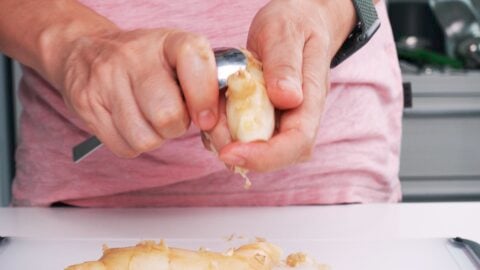 Peeling ginger using a spoon.