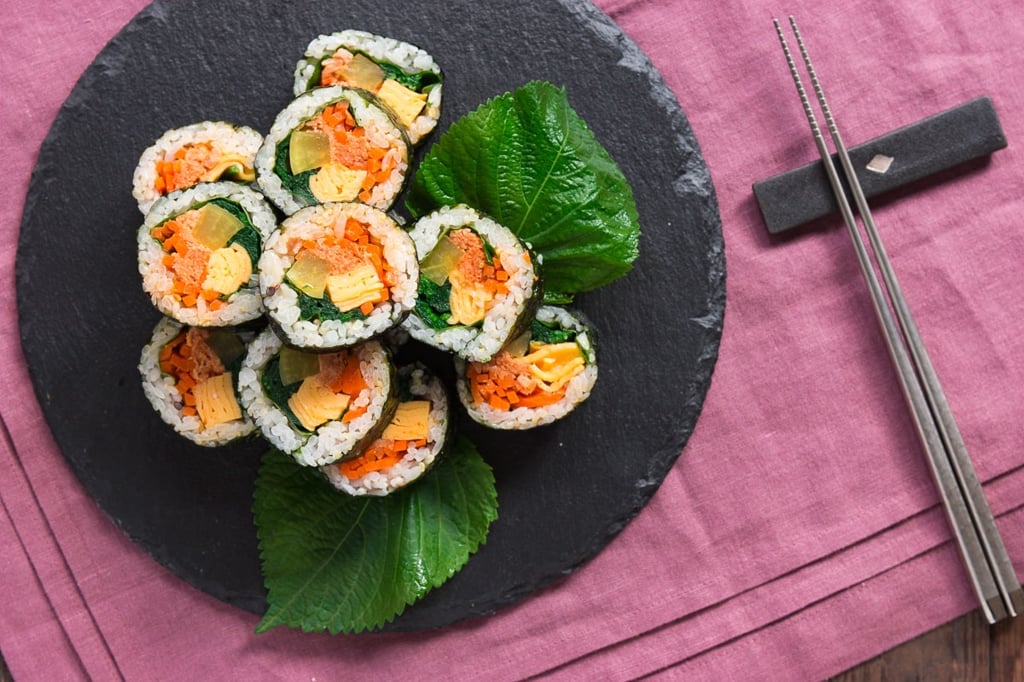 Korean gimbap rolls filled with spicy tuna, marinated carrots, kkaenip, pickled radish, omelete and spinach.