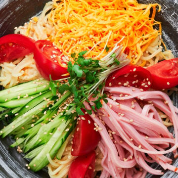 Topped with sweet tomatoes, crisp cucumbers, savory ham, and golden threads of egg, this easy ramen salad (hiyashi chuka) is the perfect summer meal.