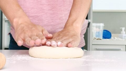 Flattening relaxed dough before rolling out.