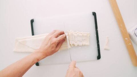 Hand-cutting udon noodles with a knife.