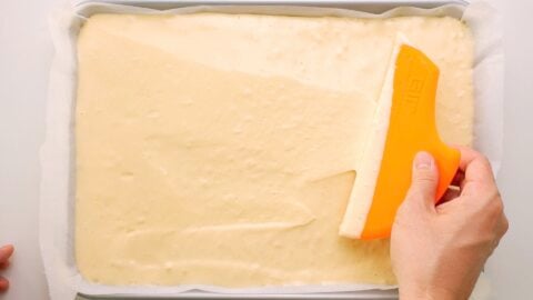 Smoothing off the surface of a sheet pan of sponge cake batter.