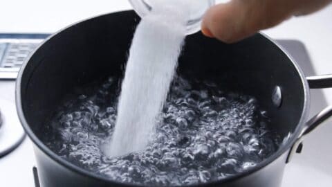 Salting boiling water for pasta.