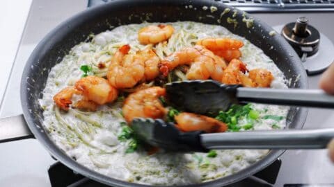 Adding shrimp and watercress to nori cream pasta.