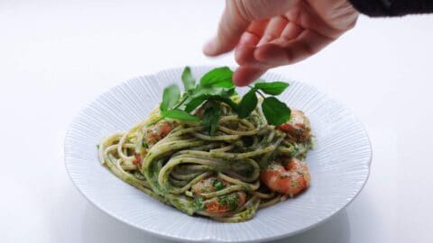 Garnishing a plate of Japanese shrimp pasta with watercress.