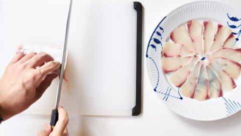 To make kanpachi Carpaccio, slice the fish as thinly as possible using a long sharp knife, and then line the bottom of a flat plate with the fish.