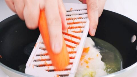 Grating carrots and onions into a pan for making Japanese curry sauce.