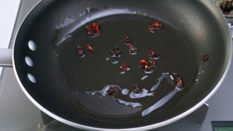 Red chili peppers and oil in a frying pan.