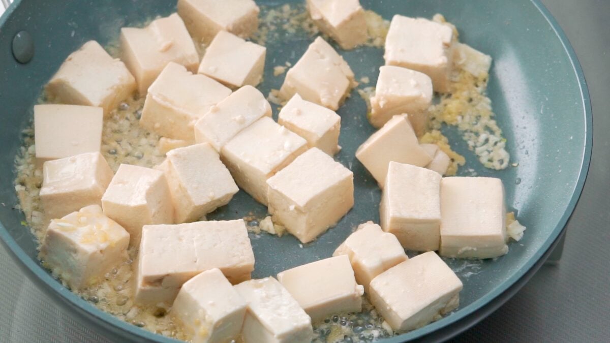 Browning marinated tofu in a frying pan.