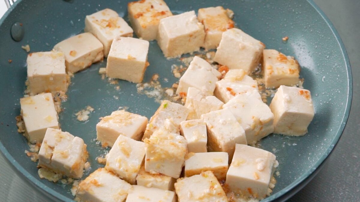 Tofu, ginger and garlic browned in a frying pan.