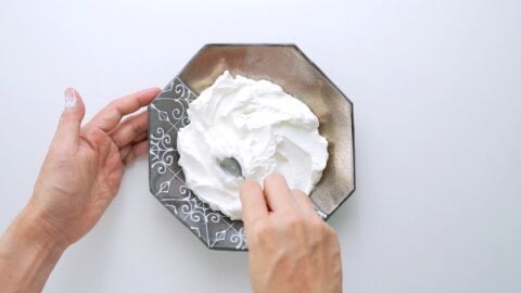 Spreading Labneh around a serving dish with s spoon.