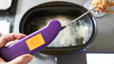 Testing the temperature of fried chicken using a purple Thermapen.