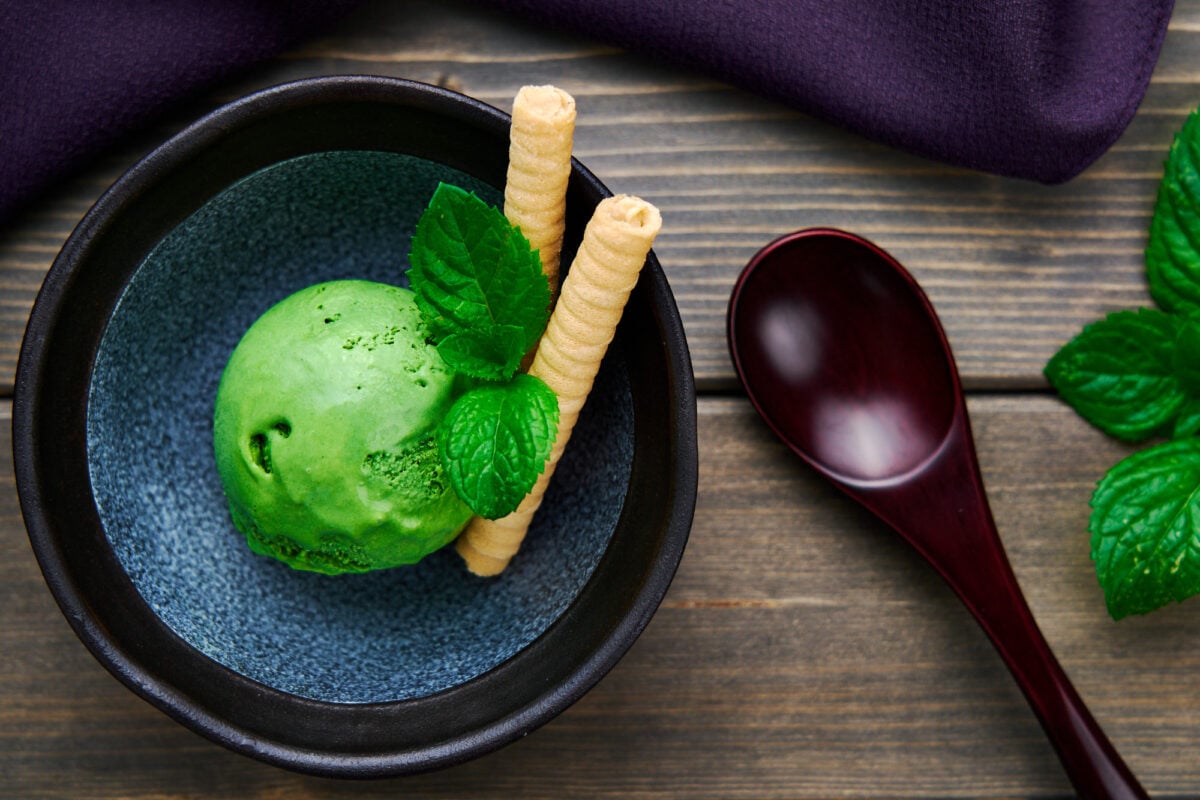 A scoop of homemade no-churn matcha ice cream with mint and cookies.