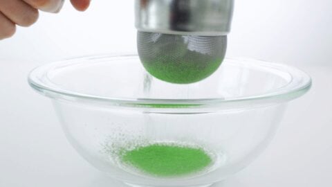 Sifting matcha into a glass bowl.