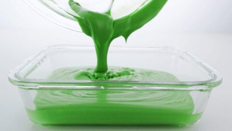 Pouring matcha ice cream base into a glass container.