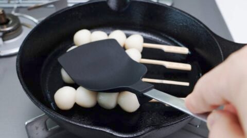 Grilling Mitarashi Dango on a cast iron skillet.