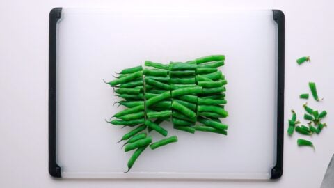 Chopped blanched green beans on cutting board.