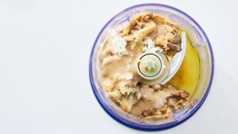 Ingredients for Mutabbal, including roasted eggplant, tahini, garlic, lemon juice and salt in a food processor.